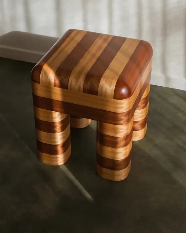 A small, four-legged stool with a striped pattern created by alternating wood tones. The top surface is rounded and the legs are cylindrical with rounded edges. The contrasting wood grain suggests a visually striking design. — 3D model
