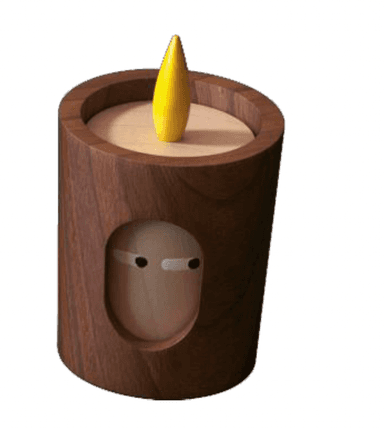A modern, minimalist decorative lamp designed to resemble a candle, featuring a cylindrical dark walnut wood body. An oval cutout on the front reveals an internal light-colored wooden element shaped like a stylized face with simple black eyes. A yellow, flame-like LED light protrudes from the top surface. — 3D model