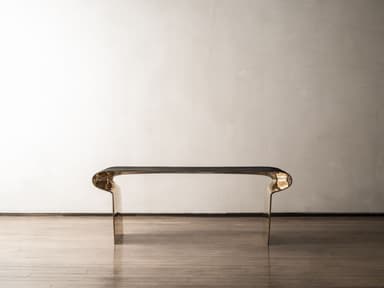 A modern sculptural console table featuring a distinctive two-tone finish. The table is formed from a single, continuous piece of material, creating a U-shaped or inverted C-shaped profile. The exterior surfaces exhibit a dark, patinated finish, while the interior curves are highly polished brass, creating a striking contrast. Its minimalist yet bold design makes it a prominent statement piece. — 3D model