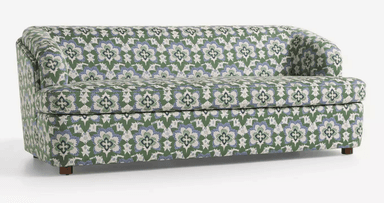 A three-seater sofa with a rounded armrest on the left side. The sofa is upholstered in a fabric with a repeating floral pattern in green, blue, and white. It has a solid base and short, wooden legs. — 3D model