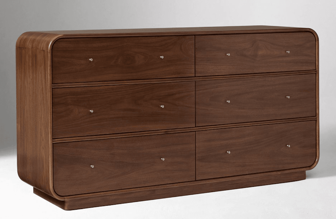 A dresser with a dark wood finish, featuring six drawers arranged in two columns of three. The top surface and sides have rounded edges, giving it a streamlined, modern appearance. Each drawer has a small, circular metallic knob. — 3D model