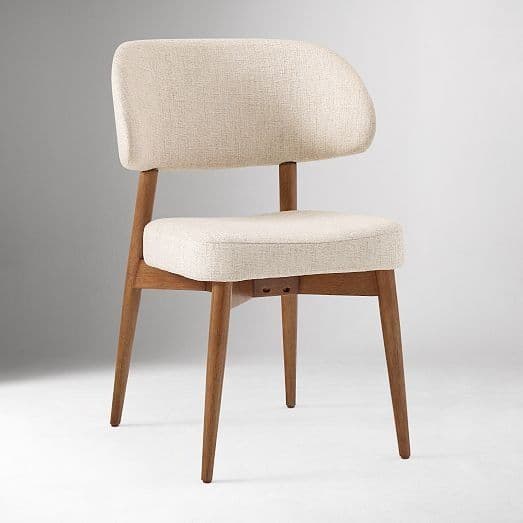 A modern upholstered chair with a curved backrest and four wooden legs. The seat and backrest are padded and covered in a textured light-colored fabric. The wooden frame is visible, forming the legs and supporting structure. The chair has a simple, elegant design. — 3D model