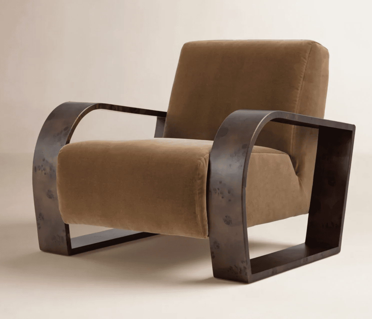 An Art Deco style armchair featuring a distinctive U-shaped wooden frame that forms both the arms and the base. The frame appears to be made from a dark, possibly burl, wood with a speckled or distressed finish. The chair is upholstered in a plush, light brown or camel-colored fabric, providing a soft contrast to the rigid wooden structure. The design emphasizes clean lines and a geometric silhouette, characteristic of the Art Deco period. — 3D model