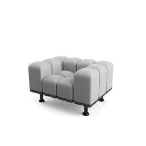 A modular armchair with a distinctive segmented upholstered form. The seat and backrest are composed of multiple rounded, pillow-like sections arranged in a grid pattern. The frame appears to be a dark, possibly metal, structure supporting the upholstered modules. It is elevated by four short, black cylindrical legs with a slight outward angle. — 3D model
