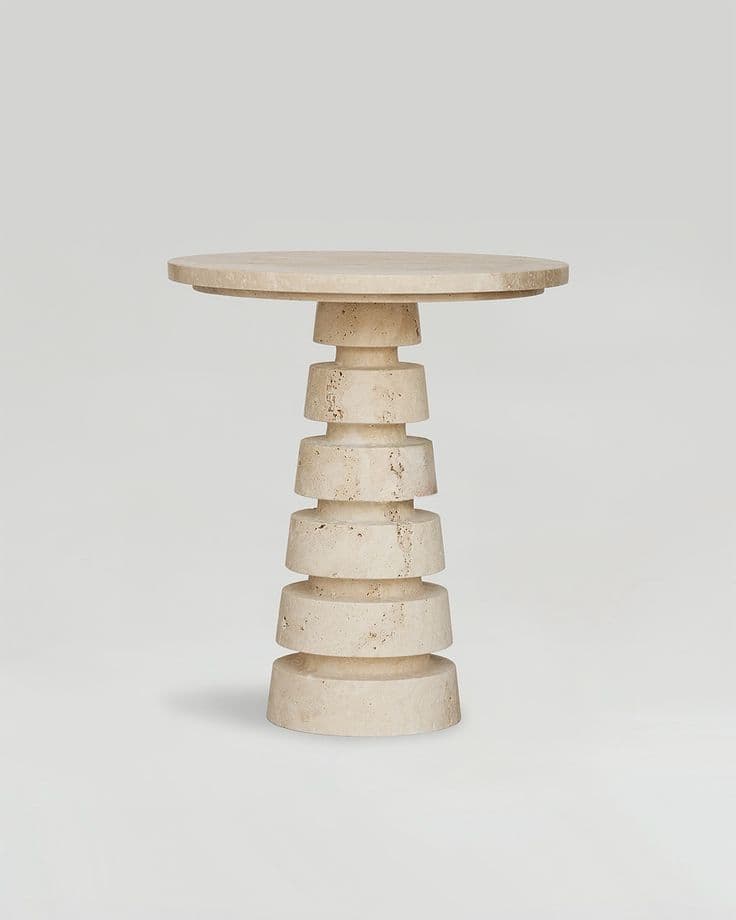 A cylindrical side table with a tiered pedestal base. The tabletop is round and flat. The pedestal is constructed from stacked, progressively wider cylindrical sections, creating a stepped effect. The material appears to be a natural stone, possibly travertine, with visible pores and variations in color. — 3D model