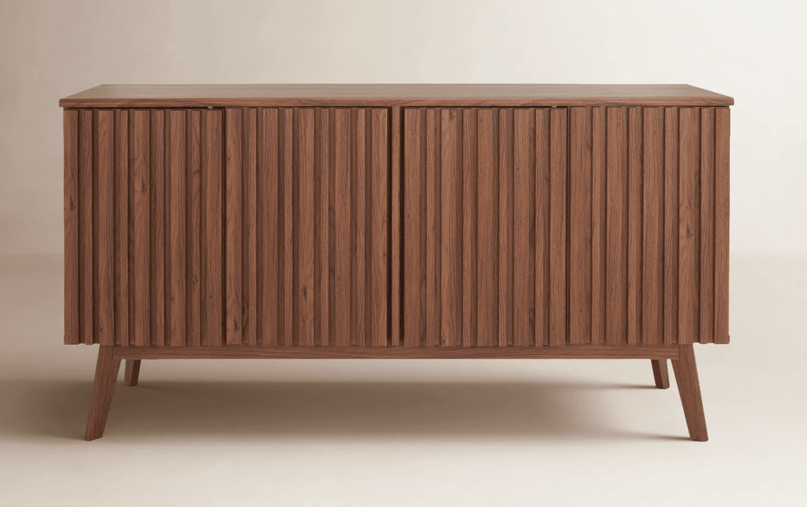 A contemporary storage cabinet crafted from dark-toned wood, featuring two doors with a distinctive fluted or reeded texture across their entire surface. The cabinet stands on four slender, splayed legs, typical of mid-century modern design, providing a light and airy aesthetic. Its clean lines and natural wood grain emphasize a minimalist yet sophisticated appeal, suitable for various interior settings. — 3D model