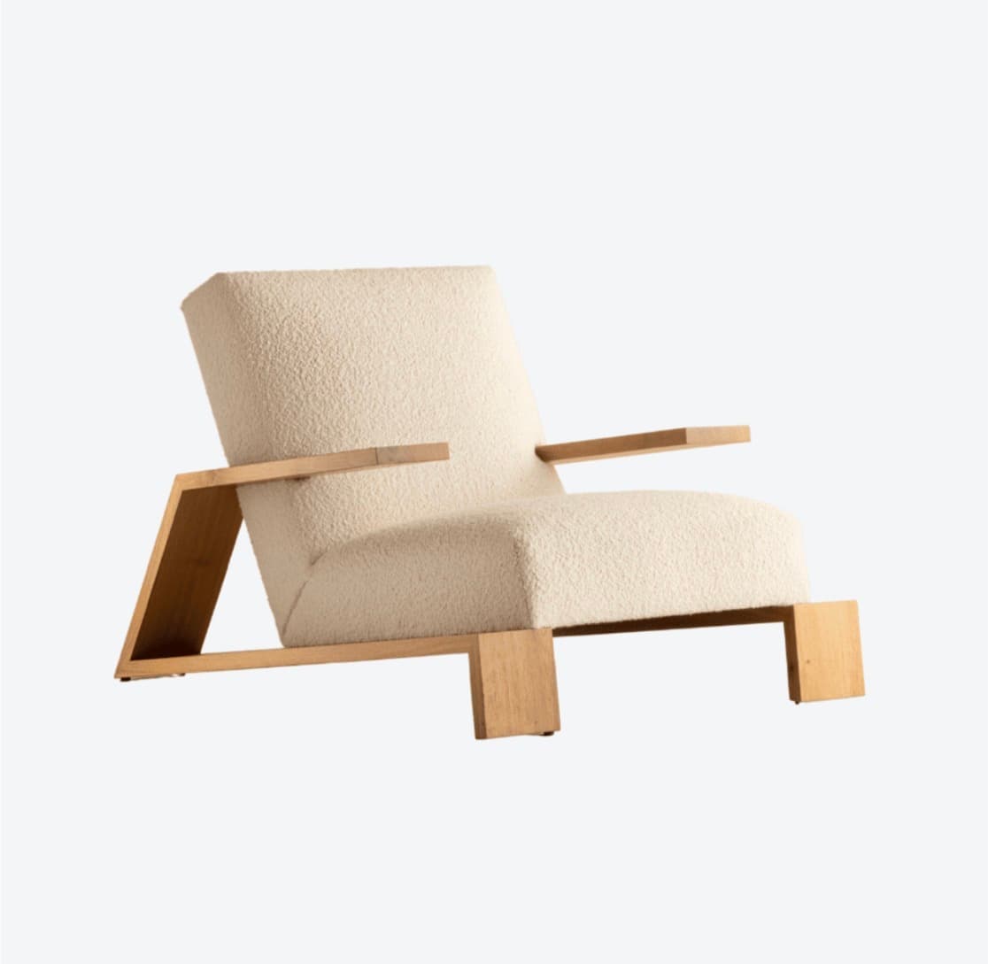 A lounge armchair featuring a plush bouclé fabric upholstery in a neutral cream color. The chair is supported by a distinctive geometric wooden frame, likely constructed from light-toned hardwood. The frame design incorporates angular supports for the arms and a low-profile base. The overall aesthetic balances comfort with modern, minimalist design. — 3D model