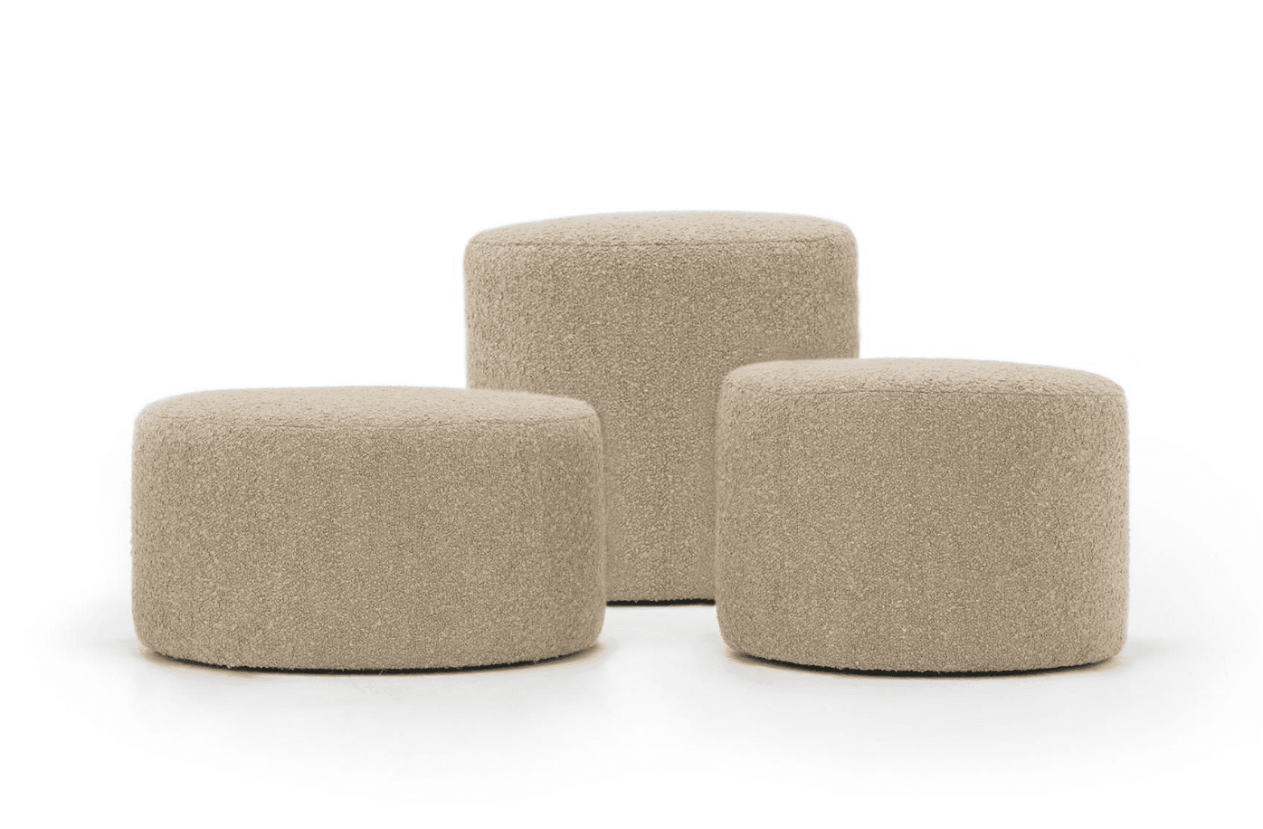 A set of three cylindrical ottomans, fully upholstered in a light beige or cream-colored boucle fabric. The ottomans vary in height, with two being shorter and one taller, suggesting a nesting or multi-use arrangement. They feature soft, rounded edges and a consistent textured finish across all pieces. — 3D model