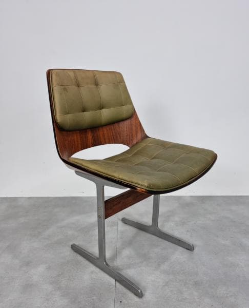 A mid-century modern dining chair with a molded plywood shell and upholstered seat and back. The chair has a distinctive curved silhouette with a cutout in the backrest. It is supported by a brushed metal base with a cantilevered design. — 3D model