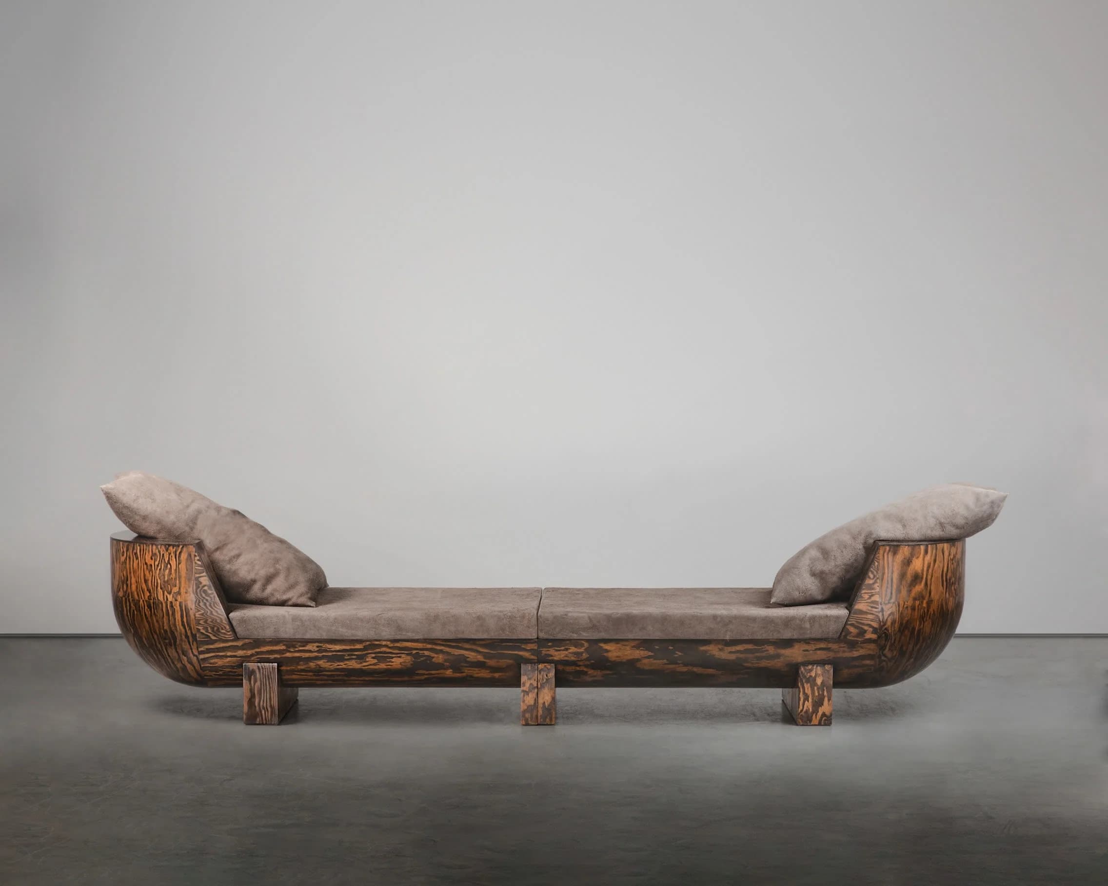 A contemporary two-seater sofa with a unique, curved wooden frame and upholstered seating. The frame exhibits a prominent wood grain pattern with a rich, dark finish. The seating and two crescent-shaped back cushions are upholstered in a textured, taupe fabric. The sofa rests on short, block-like wooden legs. — 3D model