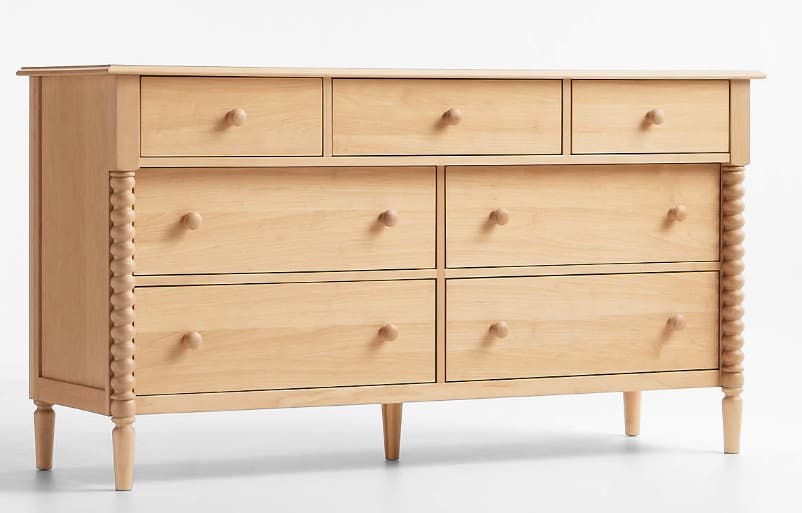 A light-colored wooden dresser featuring a total of seven drawers. The top row has three smaller drawers, and the two lower rows each have two larger drawers. The dresser is supported by four tapered legs. Decorative rope-like carving is present on the vertical edges of the dresser's sides. All drawers are fitted with small, round wooden knobs. — 3D model