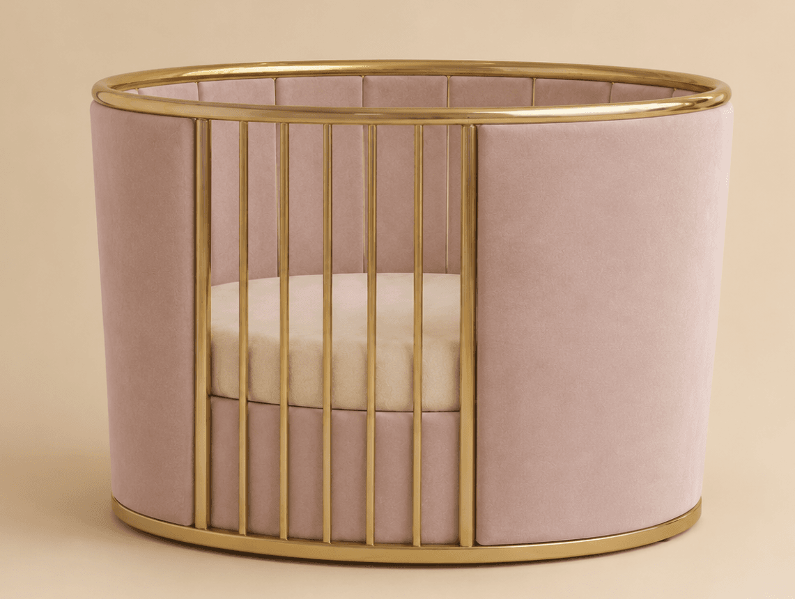 An oval-shaped baby crib featuring blush pink velvet upholstery and polished gold-toned metal accents. The crib has vertical gold bars on one side, a solid velvet-covered side, and a light-colored mattress inside. — 3D model