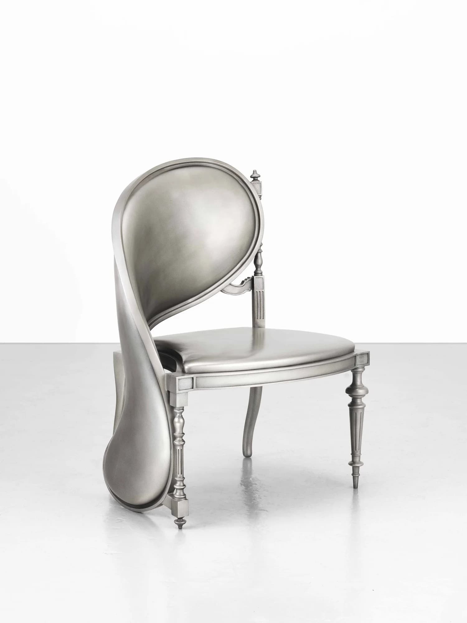 A silver-colored chair with a distinctive, flowing backrest that appears to be melting or contorting. The seat and legs maintain a more traditional, ornate design. The chair has a rounded seat and features four turned legs. The backrest is curved and smooth, with a prominent, drooping element on the left side. — 3D model