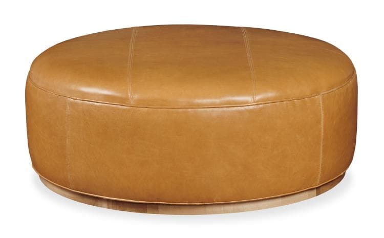 A large, oval-shaped ottoman upholstered in smooth, tan leather. It features subtle stitching details on the top surface, running in parallel lines. The base of the ottoman appears to be constructed from light-colored wood, with a visible grain pattern. The overall form is rounded and padded, suggesting a comfortable and functional piece. — 3D model