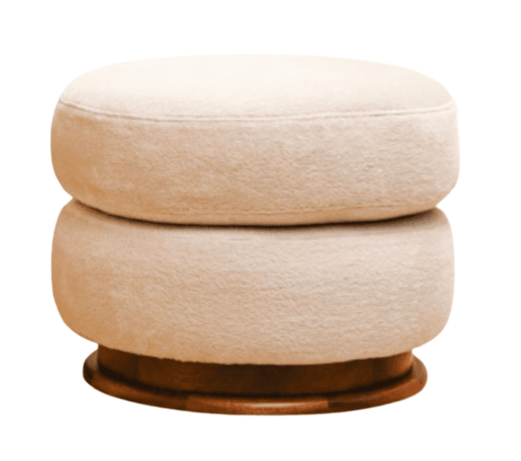 A round, upholstered ottoman featuring a stacked cylindrical design. The upholstery has a textured, possibly chenille or velvet, finish. It is supported by a circular, dark wood base that appears to be slightly elevated from the surface it rests on, suggesting a swivel mechanism or a decorative base. — 3D model