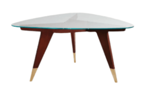 A contemporary coffee table featuring an organic, rounded triangular glass top. The clear glass top rests on a support structure from which three splayed, tapered wooden legs extend outwards. Each leg is finished with a distinct brass sabot, adding a touch of metallic accent. The design suggests a strong influence from Mid-Century Modern aesthetics, combining natural materials with sleek lines and a distinctive form. — 3D model