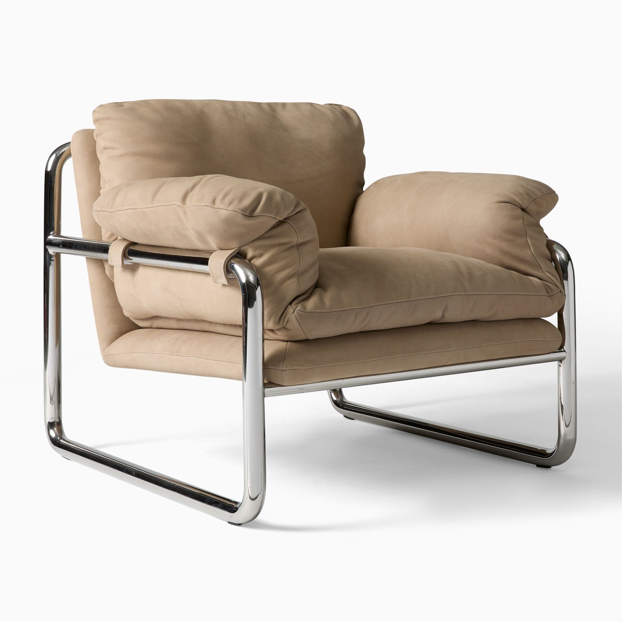 A modern armchair featuring a tubular chrome-plated steel frame and plush, upholstered cushions in a light beige fabric. The frame has a cantilevered design, providing support for the seat and backrest. The cushions appear to be generously filled, creating a comfortable and inviting appearance. The armrests are integrated into the frame structure. — 3D model