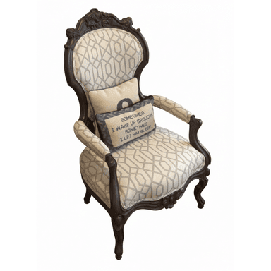 An ornate upholstered armchair featuring a dark, intricately carved wooden frame with rococo-inspired motifs on the crest rail and apron, and elegant cabriole legs. The seat, backrest, and armrests are upholstered in a light-colored fabric with a contemporary geometric pattern, primarily in cream and light grey tones. Two decorative throw pillows are placed on the seat and back. — 3D model (AI enhanced source)