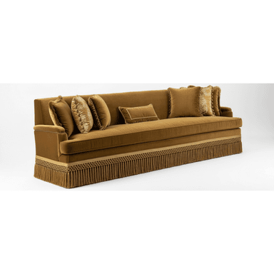 A large, rectangular sofa upholstered in golden-brown velvet fabric, featuring a full decorative fringe skirt around the base and multiple plush throw pillows. — 3D model (AI enhanced source)