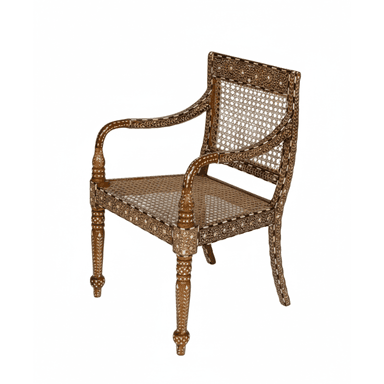 An Anglo-Indian style armchair featuring a dark-stained wooden frame extensively decorated with intricate bone or ivory inlay. It has a woven cane seat and a matching cane backrest. The arms are curved and inlaid, and the front legs are turned with ornate carvings, terminating in bun feet. The overall design is highly decorative and showcases traditional craftsmanship. — 3D model (AI enhanced source)