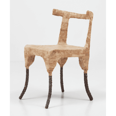 A unique, organically shaped chair with a textured surface. The seat and backrest appear to be constructed from a material resembling paper mâché or a similar composite, formed into irregular segments. The legs are distinct, appearing to be made of a darker, possibly metal or wood material, with a rough, bark-like texture. The overall design is abstract and sculptural. — 3D model (AI enhanced source)