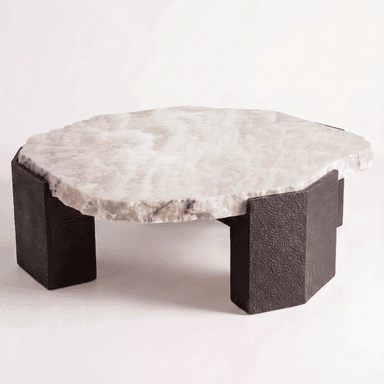 A low-profile coffee table featuring a thick, organically shaped tabletop made from light-colored onyx with natural veining and rough, unpolished edges. The top rests upon four substantial, rectangular block legs made of a dark, textured material, possibly cast metal or resin, giving the table a robust and earthy aesthetic. — 3D model (AI enhanced source)