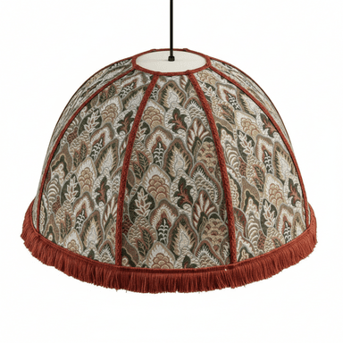 A domed pendant lampshade featuring a richly patterned textile surface. The fabric displays an intricate jacquard weave with stylized foliage and floral motifs in shades of green, brown, beige, and off-white. The lampshade is segmented by vertical orange-red braided trim, and its bottom edge is adorned with a matching orange-red fringe. — 3D model (AI enhanced source)