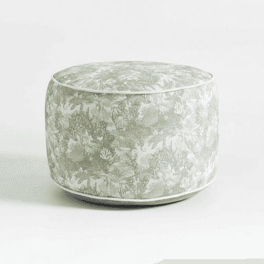 A fully upholstered, cylindrical ottoman featuring a light green and white fabric with an intricate aquatic or coral-themed pattern. It is defined by crisp white piping along its top and bottom circular edges, providing a tailored finish to its cushioned form. — 3D model (AI enhanced source)