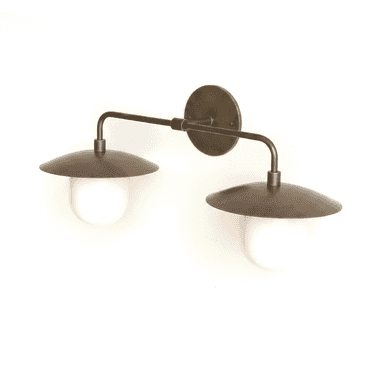 A double arm wall sconce featuring an aged brass or bronze finish. It consists of a circular backplate from which a horizontal arm extends. This arm then branches into two downward-curving arms, each holding a light source. Each light source is composed of a disc-shaped metal shade resting above a frosted white glass globe diffuser. — 3D model (AI enhanced source)