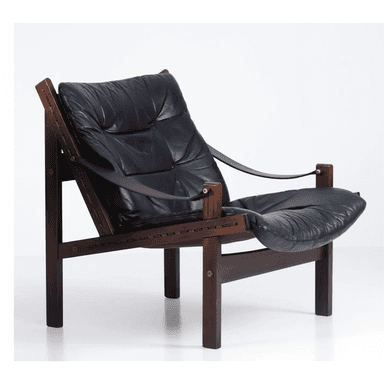 A low-slung lounge chair featuring a dark-stained solid wood frame, likely rosewood, with exposed joinery. It is fitted with thick, tufted black leather cushions for both the seat and back, suspended within the frame. Leather straps form the armrests, secured by brass hardware. — 3D model (AI enhanced source)