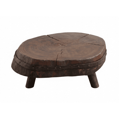A rustic and primitive low table, likely serving as a coffee table or accent table, crafted from a thick, irregularly shaped slab of wood, resembling a cross-section of a tree stump. The top surface displays prominent wood grain and natural radial cracks, indicating its organic origin and age. A distressed metal band with visible rivets encircles the perimeter, securing the wood and contributing to its rugged aesthetic. The table stands on three short, sturdy, tapered wooden legs. — 3D model (AI enhanced source)