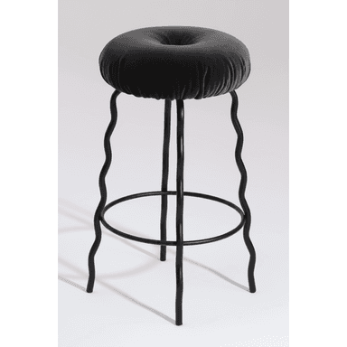 A modern bar stool featuring a deeply cushioned, round seat upholstered in dark grey velvet, distinguished by a central button tuft. The stool's black metal frame consists of four legs, each uniquely designed with a continuous wavy or squiggly profile, extending from beneath the seat to the floor. A circular black metal footrest connects the legs approximately one-third of the way up from the base, providing stability and support. The overall design conveys a playful yet sophisticated contemporary aesthetic. — 3D model (AI enhanced source)