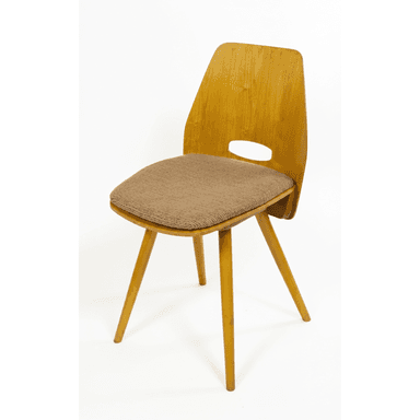 A vintage mid-century modern side chair featuring a bent plywood frame with a light wood veneer finish. It has a distinctive curved backrest with an oval cutout serving as a handle. The seat is upholstered in a textured, light brown fabric, and the chair stands on four splayed, tapered wooden legs. — 3D model (AI enhanced source)