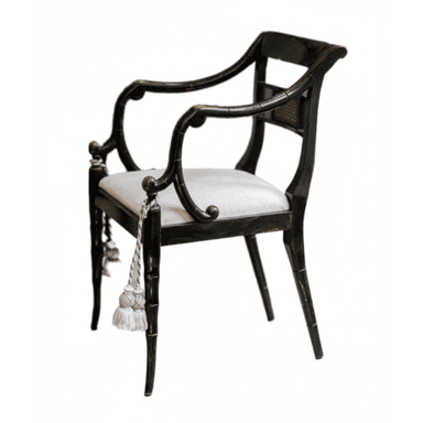 An armchair featuring an ebonized, faux bamboo-style wooden frame. The backrest includes a rectangular woven cane panel, while the arms are elegantly curved, flowing from the back. The seat is upholstered in a light-colored, possibly off-white or cream, fabric. The legs are tapered and also mimic the bamboo motif, with the front legs adorned with decorative tassels. The overall aesthetic suggests a Regency or Chinoiserie influence. — 3D model (AI enhanced source)