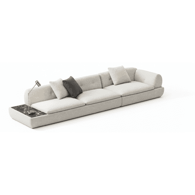 A long, contemporary modular sofa upholstered in a light, textured fabric, likely bouclé. It features multiple seat and back cushions, some with button tufting. An integrated dark, veined marble side table is positioned at one end, supporting a small, silver-toned task lamp. The sofa has a low-profile design with soft, rounded edges. — 3D model (AI enhanced source)