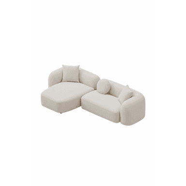 A contemporary L-shaped sectional sofa consisting of two modular pieces: a main sofa unit and an extended chaise lounge. The entire piece is upholstered in a textured, light-colored boucle fabric. It features a low-profile design with rounded edges and soft, voluminous forms, giving it a plush appearance. The sofa includes three accent pillows: two square and one cylindrical bolster pillow, all matching the primary upholstery. The design emphasizes comfort and a minimalist, inviting aesthetic. — 3D model (AI enhanced source)
