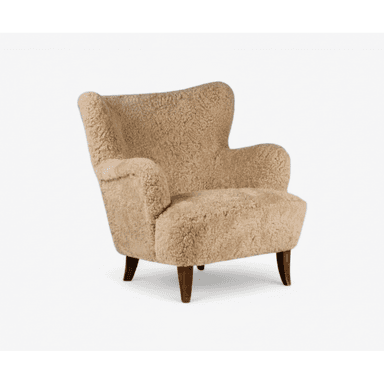 A contemporary lounge chair upholstered in a shaggy, light-colored sheepskin or bouclé fabric, featuring a rounded, high back, integrated armrests, and short, dark wooden legs. — 3D model (AI enhanced source)
