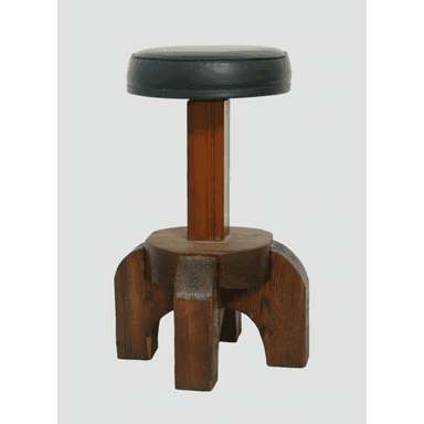 A robust, brutalist-style stool featuring a circular, dark upholstered seat atop a thick, central wooden column. The base is constructed from heavy, blocky pieces of dark-stained wood, forming a sturdy, four-legged support structure with a distinct, architectural aesthetic. — 3D model (AI enhanced source)