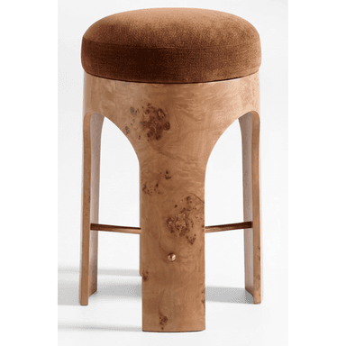 A contemporary stool featuring a round, plush brown upholstered seat set upon a distinctive burl wood veneer base. The base forms a continuous, curved structure with arched cutouts, creating a modern and sculptural silhouette. A brass bar serves as a footrest, extending between two of the wooden supports. — 3D model (AI enhanced source)