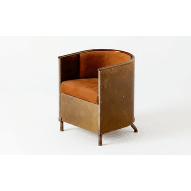 An industrial-style barrel armchair featuring a curved metal frame with visible rivets and a patinated finish. The seat and backrest are upholstered in a warm, burnt orange fabric or leather, providing a contrasting texture and color. The chair sits on short, splayed cylindrical legs, maintaining a compact and robust profile. — 3D model (AI enhanced source)