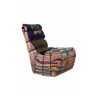 A unique lounge chair constructed entirely from tightly bundled and strapped clothing and textile scraps, forming a distinct backrest and seat. The various fabrics create a multicolored, textured surface, held together by visible black strapping bands. — 3D model (AI enhanced source)