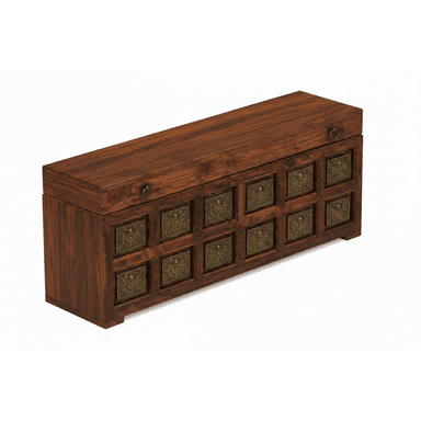 A rectangular, dark-stained wooden chest featuring a lift-top lid and decorative embossed brass panels on the front and sides. The lid is equipped with two brass ring pulls. The front facade displays twelve square brass panels arranged in a grid pattern, each with an intricate, symmetrical design. The chest rests on a short, integrated plinth base. — 3D model (AI enhanced source)