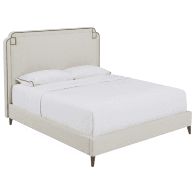 A contemporary upholstered bed featuring a distinctive headboard and a matching upholstered frame. The headboard has a gently curved top edge with subtle cutouts and is adorned with a continuous line of brass or bronze nailhead trim, which also forms decorative square accents at the upper corners. The entire bed frame, including the side rails and footboard, is upholstered in a light, neutral-toned fabric. The bed is supported by four dark, tapered wooden legs and is presented with white bedding. — 3D model (AI enhanced source)