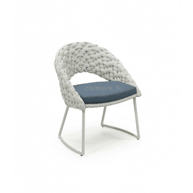 A modern outdoor accent chair featuring a distinctive hand-woven rope body in light grey over a minimalist powder-coated metal frame. It includes a dark blue fabric seat cushion with a subtle dotted pattern, providing comfort and a contrasting color element. The chair's back and armrests are integrated into a single, embracing woven form. — 3D model (AI enhanced source)