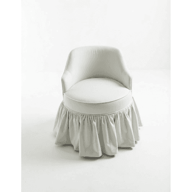 A compact, fully upholstered chair with a rounded back, low armrests, and a distinctive ruffled skirt covering its base, presented in a light, neutral fabric. — 3D model (AI enhanced source)