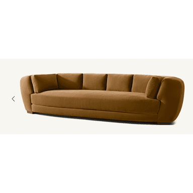 A contemporary, elongated sofa featuring a distinctively curved silhouette. It is upholstered in a rich, warm camel-brown velvet-like fabric, presenting a plush and inviting appearance. The sofa includes deep, individual seat cushions and five separate back cushions, providing ample comfort and support. Its wide, rounded armrests seamlessly integrate with the backrest, contributing to the sofa's organic and fluid form. The design rests on a low-profile base with discreet, recessed wooden feet, creating a perception of floating above the ground. — 3D model (AI enhanced source)