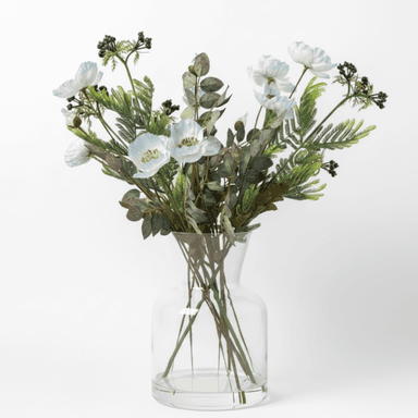 A clear glass vase containing an artificial floral arrangement. The arrangement features white poppy-like flowers, dark green fern fronds, eucalyptus leaves with reddish hues, and clusters of small dark berries. The vase has a fluted neck and a sturdy, rounded base, allowing the stems of the artificial plants to be visible through the transparent glass. — 3D model (AI enhanced source)