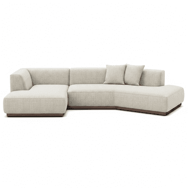 A contemporary sectional sofa featuring a light beige fabric upholstery, a low-profile design, and a dark wooden plinth base. It consists of multiple modules, including a main sofa section and an integrated chaise lounge, with subtly rounded edges. Two matching square throw pillows are included. — 3D model (AI enhanced source)