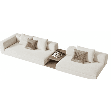 A contemporary modular sectional sofa upholstered in a light-toned, textured boucle-style fabric, featuring two expansive seating sections. An integrated two-tiered wooden side table connects and separates the sofa components, offering a functional surface within the seating arrangement. The design is characterized by its low-profile silhouette and clean lines. — 3D model (AI enhanced source)