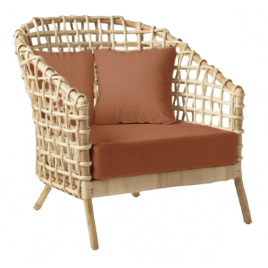 A contemporary lounge chair constructed from natural woven rattan, featuring an open, grid-like pattern on its curved back and armrests. It is furnished with a thick, flat seat cushion and two smaller back cushions, all upholstered in a solid terracotta-colored fabric. The chair rests on four slightly splayed, cylindrical rattan legs. — 3D model (AI enhanced source)